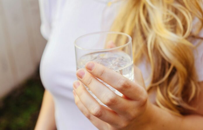 Photo by Giorgio Trovato a woman holding a glass of water in her hand