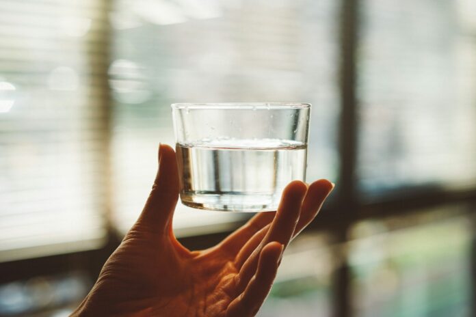 Photo by Manki Kim person holding clear glass cup with half-filled water