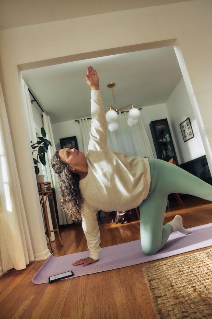 A woman does a yoga pose on a mat.
