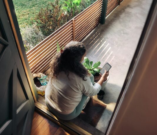 만성피로, 작은 습관 변화로 극복… 한국 일상을 위한 실천 전략 Woman sitting on balcony with smartphone