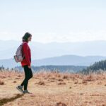 일과 건강, 균형 잡기…직장인을 위한 ‘마이크로 웰니스’ 실천법 a man with a backpack walking across a dry grass covered field